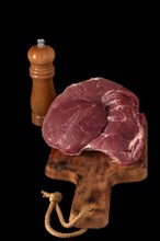 Raw beef tenderloin on a wooden board isolated on black background and copy space