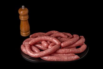 Homemade meat sausages with pepper shaker isolated on black background and copy space