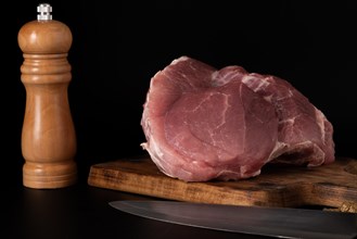 Raw beef tenderloin on a wooden board isolated on black background and copy space