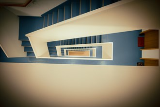 Staircase with white banister and blue vinyl floor from top to bottom