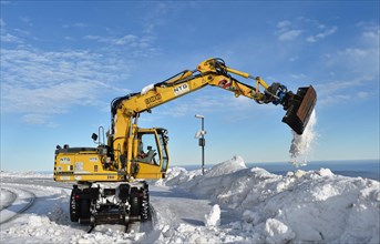 Two-way excavator clears the tracks of the Harz narrow-gauge railway from snow on the Brocken