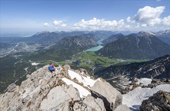 Hiker looking down from Thaneller to Plansee and eastern Lechtal Alps