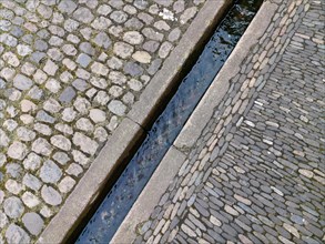 Water gutter in the cobblestones in the pedestrian zone of a city