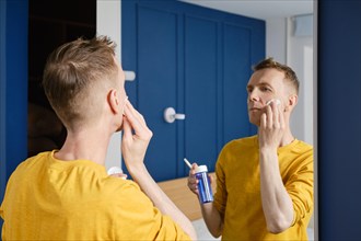 Middle aged man cleaning face with lotion using cotton pad