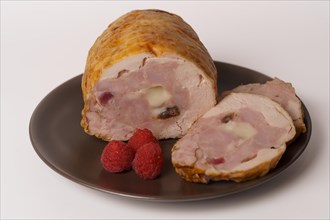 Close-up of a chicken stuffed with raspberry and goat cheese with a bowl of raspberry sauce isolated on white background