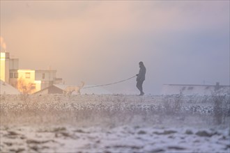 Man with dog in icy cold in the snow at sunrise