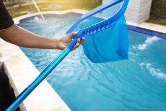 Person with skimmer cleaning pool