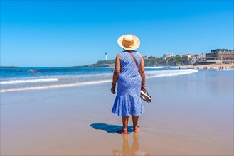 An elderly woman walking on the beach