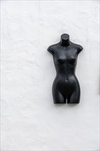 Black plastic torso for fashion clothing on white wall