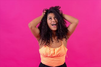 Curly-haired woman in summer clothes on a pink background having fun