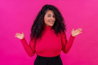 Smiling curly-haired woman posing on a pink background