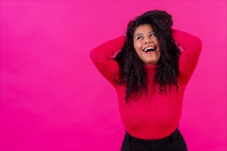 Curly-haired woman smiling on a pink background