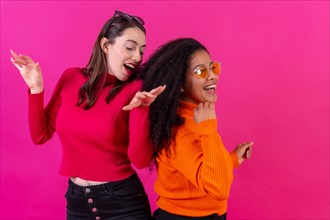 Female friends in sunglasses having fun pink background