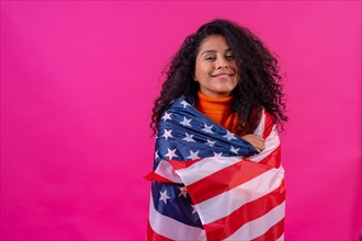Portrait of a curly-haired woman smiling with the usa flag on a pink background