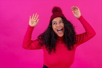 Portrait curly-haired woman in a wool hat on a pink background having fun