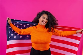 Curly-haired woman smiling with usa flag on a pink background