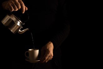 Man's hands serving coffee in dark food shadows