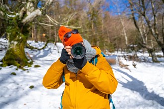 Portrait of a photographer taking winter photos in the mountains with snow doing a trekking with a backpack