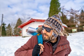 Man drinking coffee from a hot thermos in winter in the snow before starting the trekking