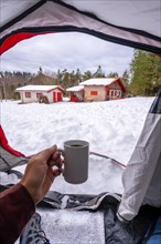 Having a coffee in a cup inside a tent on a winter morning