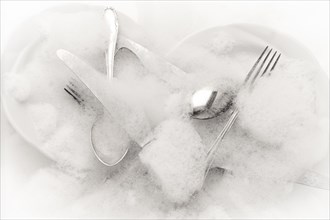 Freshly washed crockery and cutlery in soapy water