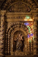 Coloured light shines on statue of saint