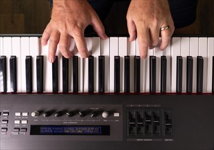 Male hands practicing on the electronic piano keyboard
