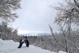 View from the mountain Moerschieder Burr in the Hunsrueck-Hochwald National Park of the snow-covered landscape with snowshoes in the foreground