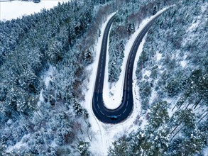 Aerial view of an S-curve in the forest with snow