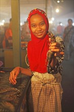 Malaysian woman with headscarf showing a crayfish at Filipino night market