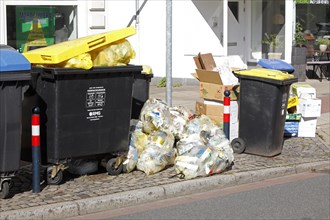 Yellow bags and yellow bins for plastic waste standing on the street