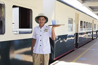 Steward in work uniform of North Borneo Railway serving drinks
