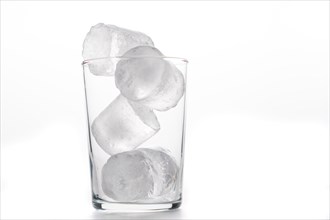 Glass tumbler with ice cubes foreground white background and copy space
