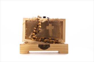Wooden christian rosary in a box with raffia white background and copy space