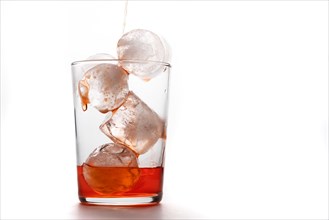Crystal glass with ices pouring red cocktail on white background and copy space