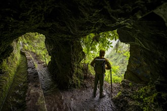 Hikers on a trail along a levada through a tunnel