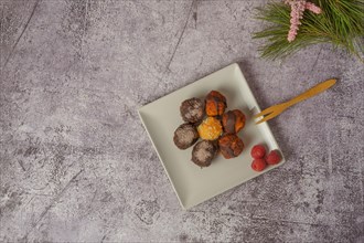Sweet truffles of different flavors on a white ceramic plate