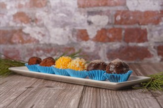 Sweet truffles in different flavors on a white ceramic tray on a wooden table