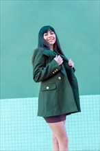 Brunette model smiling in a streetyle in a green jacket