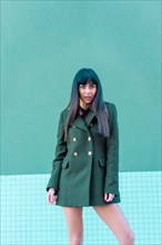 Brunette model in a streetyle on the street with a green jacket