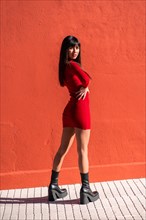 Posing brunette girl smiling in a dress and black leather boots in spring