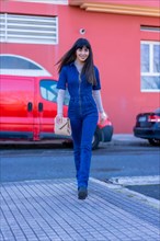 Posing of a brunette model walking down the street with a denim suit