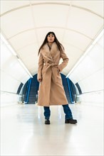 Posing of a beautiful brunette girl entering the subway with a jacket in winter