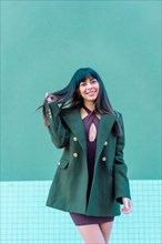 Brunette model smiling in a streetyle in a green jacket
