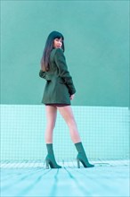 Brunette model smiling in a streetyle by the street with a jacket and green boots