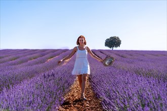 Lifestyle of a woman smiling in a summer lavender field wearing a white dress