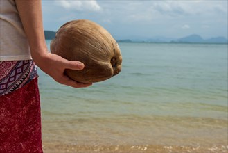 Young man holding a coconut on the beach