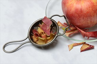 Apple peel tea in tea strainer and apple