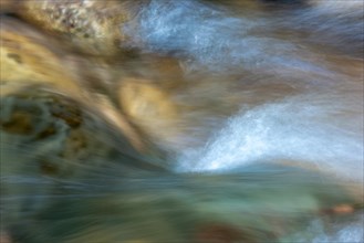 Blurry water flow in a mountain stream in a cool