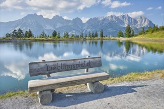 Bench in front of Astbergsee with reflection of the mountain panorama